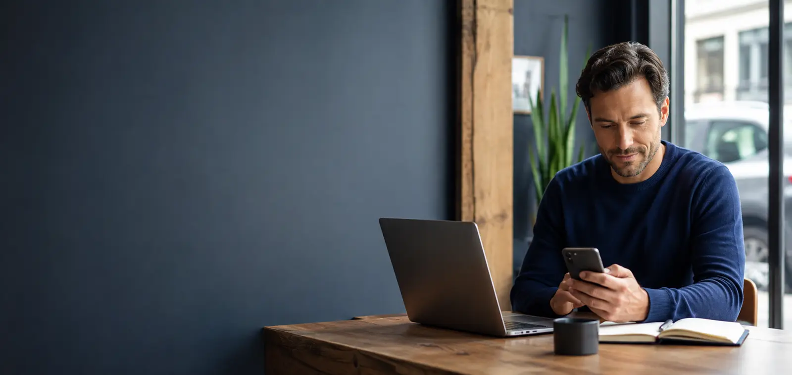 Professional reviewing follow-up from his phone beside his laptop
